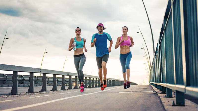 Três pessoas fazer jogging numa ponte